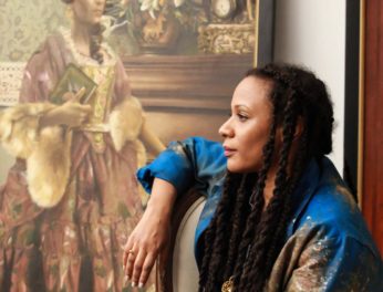 An image of Elizabeth Colomba standing next to a painting.